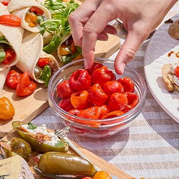 Hand picking Peppadew peppers from a bowl.